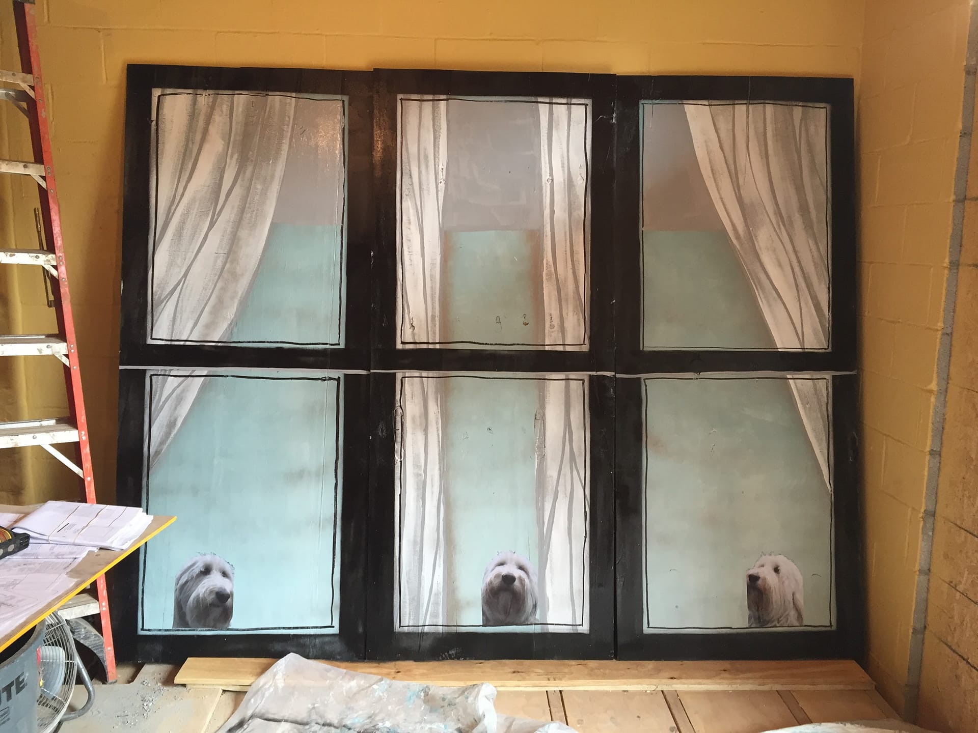 Three wood boards painted with faux windows, curtains, and an image of a dog looking out of each fake window.