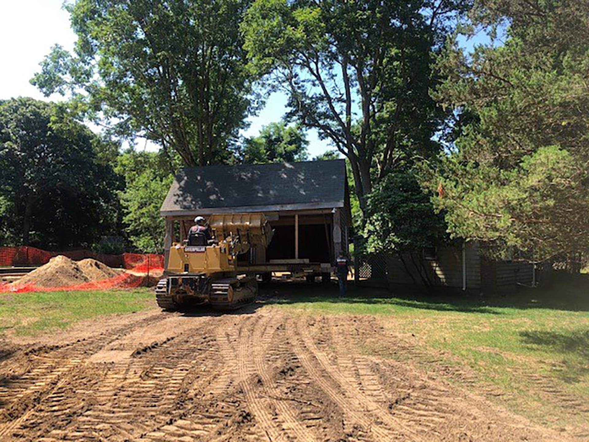 Shed being moved across a Hamptons yard with a track loader.