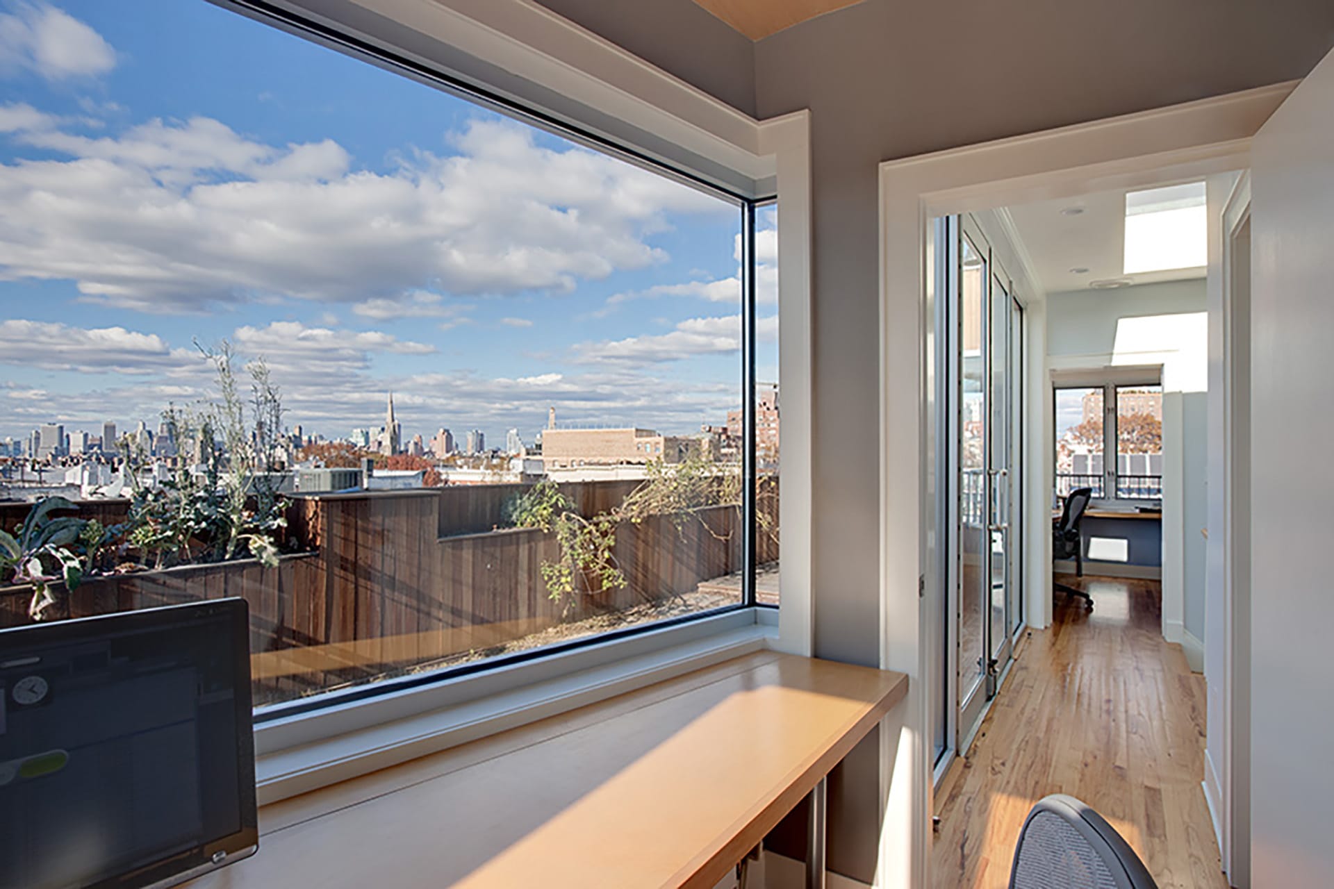 View of Manhattan skyline through a large glass window in a penthouse office.