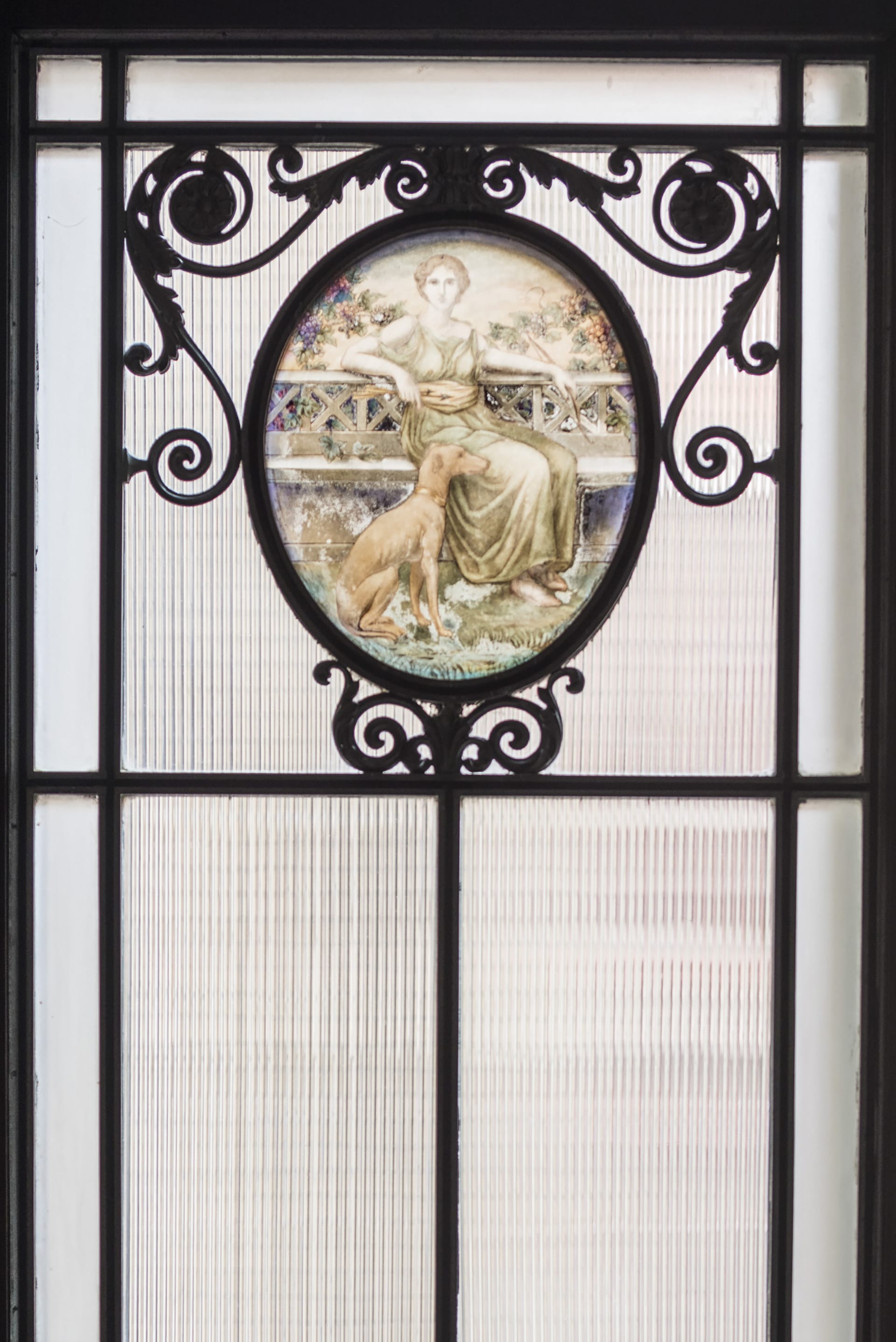 Detail shot of leaded glass windows with a detailed image of a woman and dog