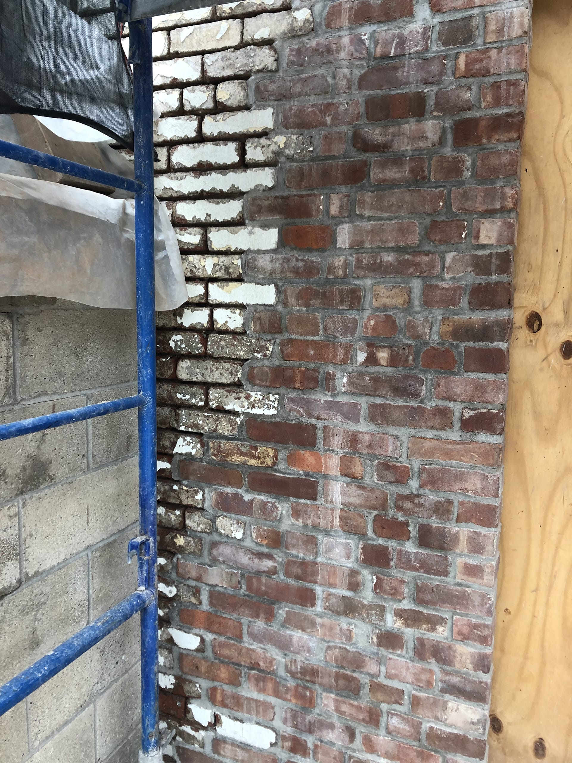 Brick next to a window opening in the process of removing the weatherproof coating from on top of it