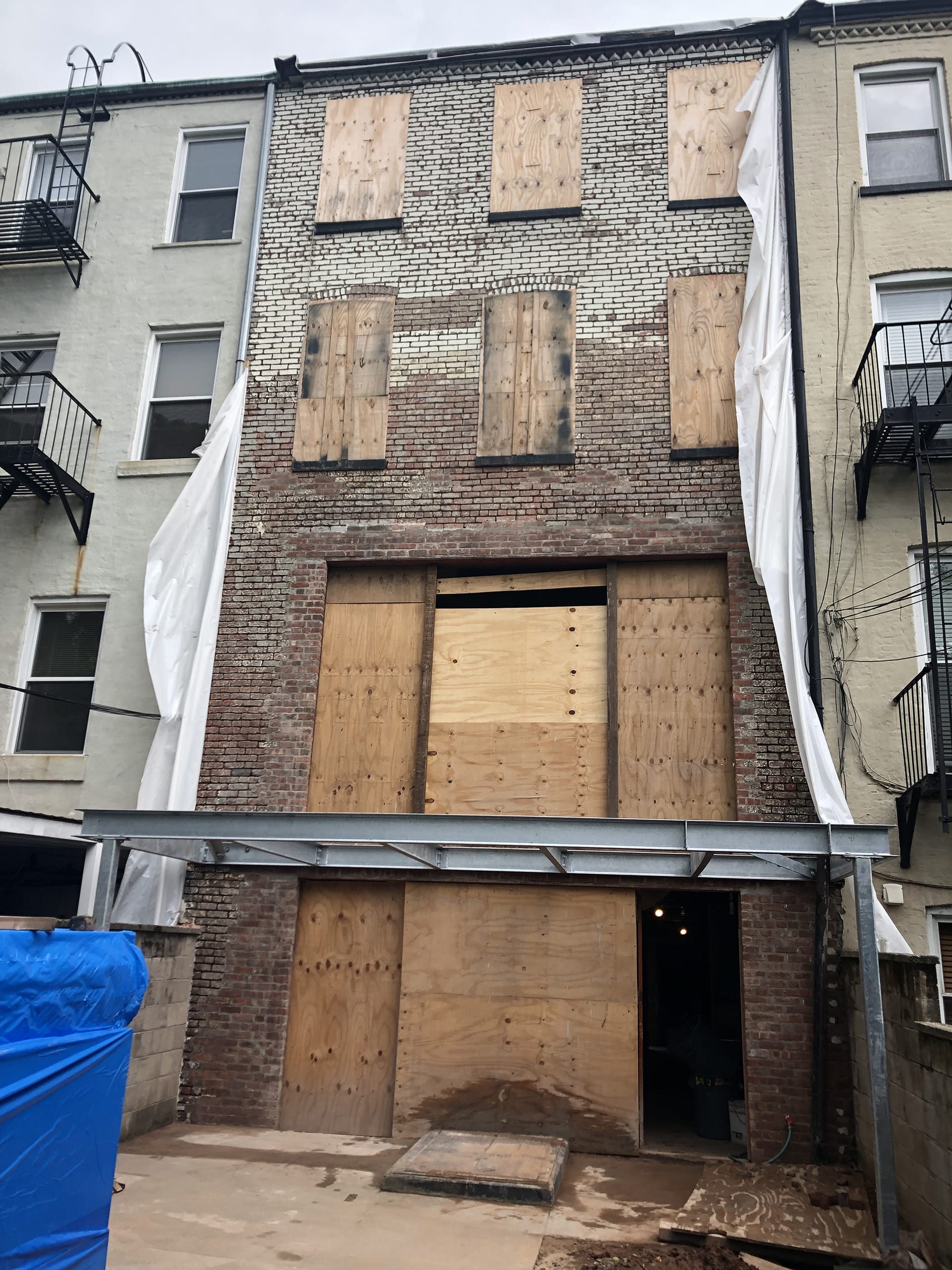 Rear facade of a brick Carroll Gardens townhouse during construction, after brick has been stripped of weatherproof coating and is in the process of being repointed
