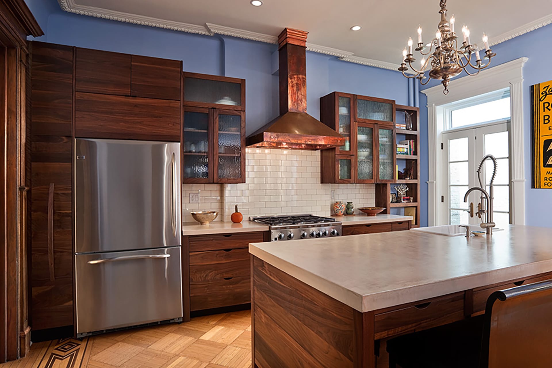 Kitchen with lilac paint, dark wood cabinetry, a copper range hood, and chandelier above the island.