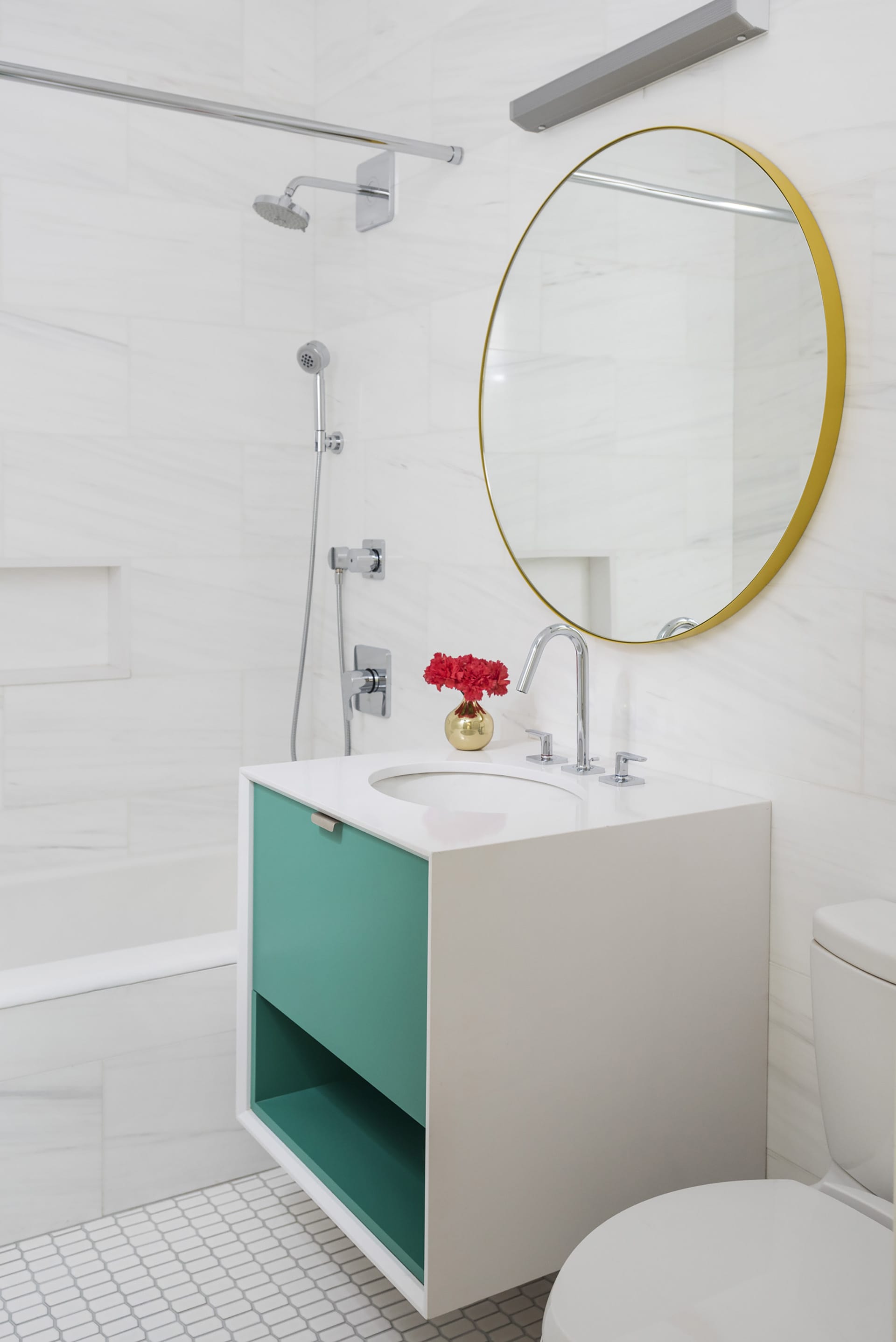 Floating vanity in an all-white bathroom with teal drawers