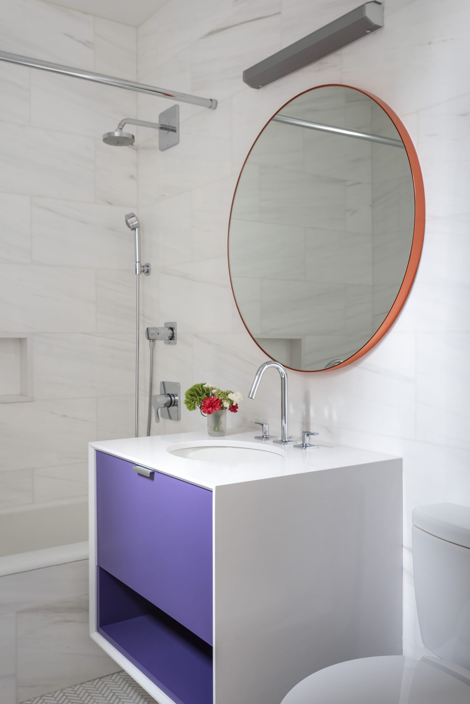 Floating vanity in an all-white bathroom with purple drawers