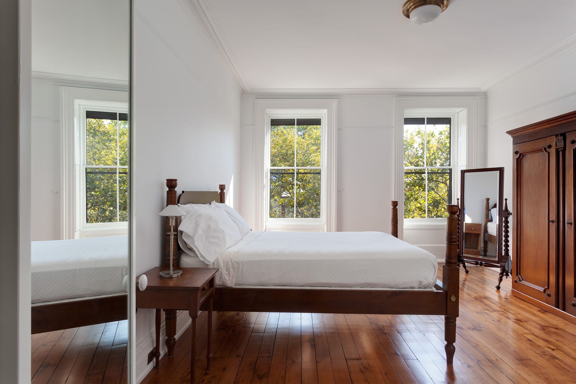 A bedroom in a Brooklyn Heights home with dark wood floors, wardrobe, and four-post bed