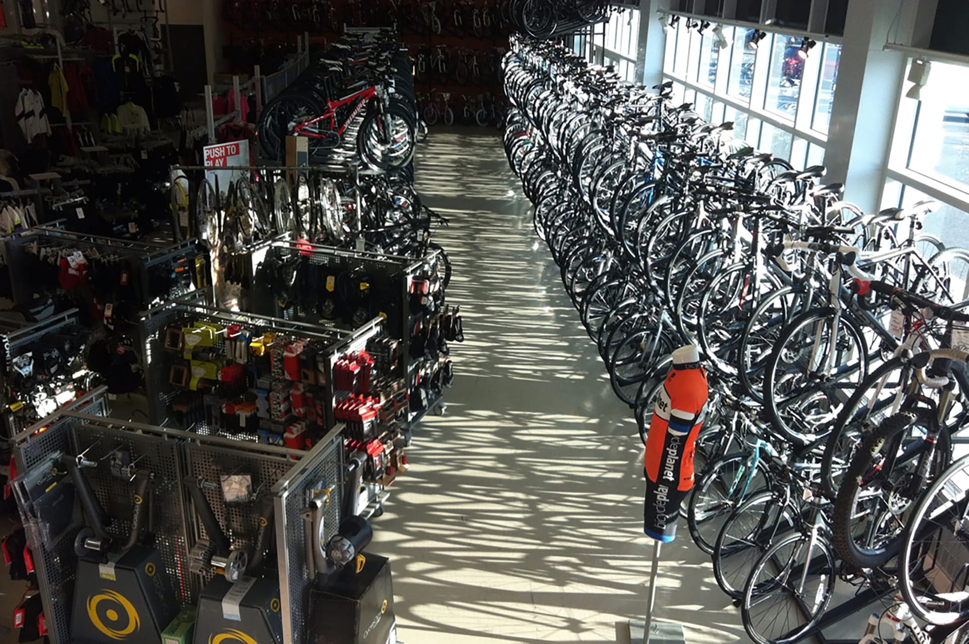 Looking down on the aisle of a bike shop, with two rows of bikes stacked on top of each other.