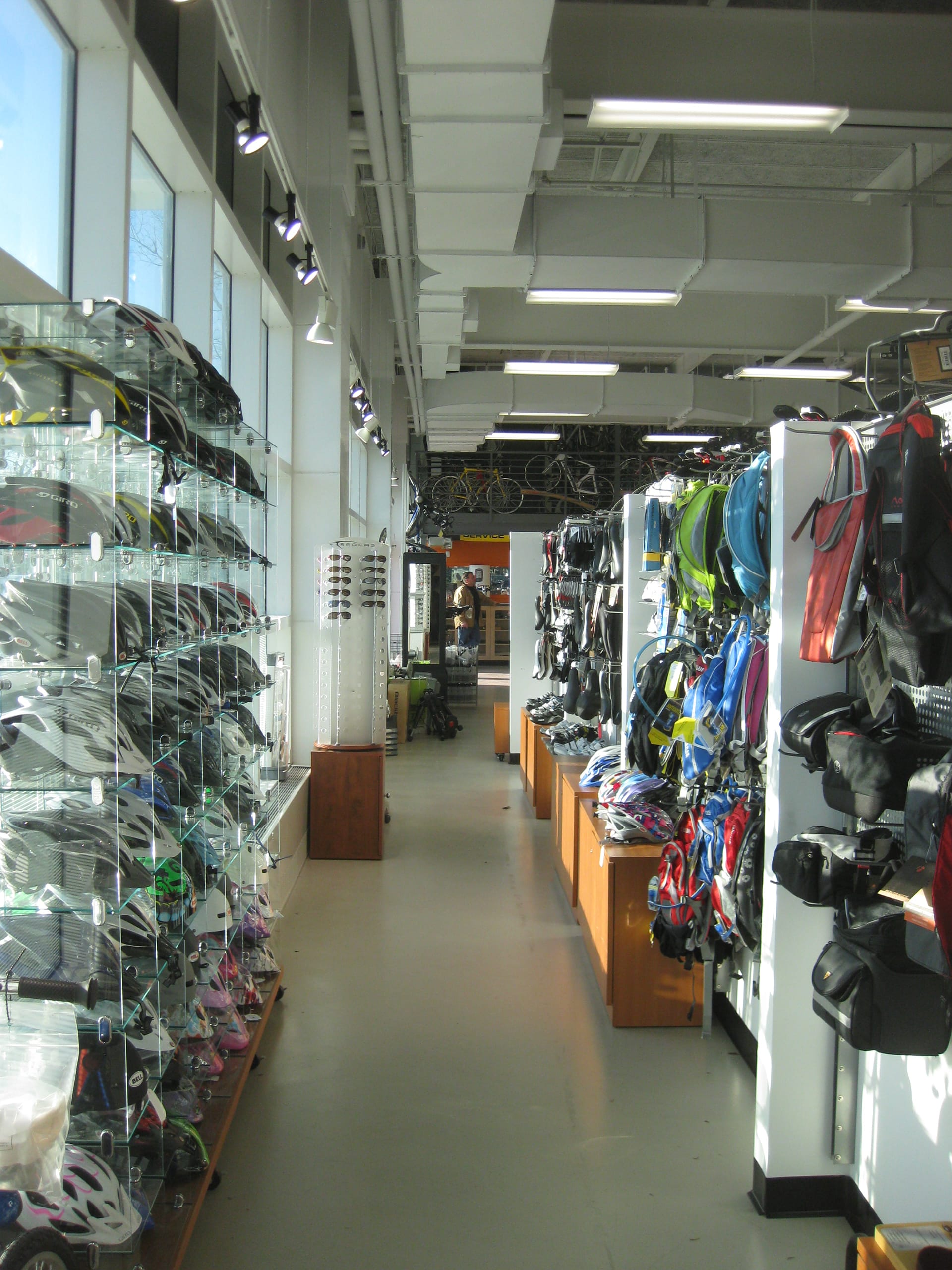 Rows of helmets, bags, and bike accessories in a bicycle shop.