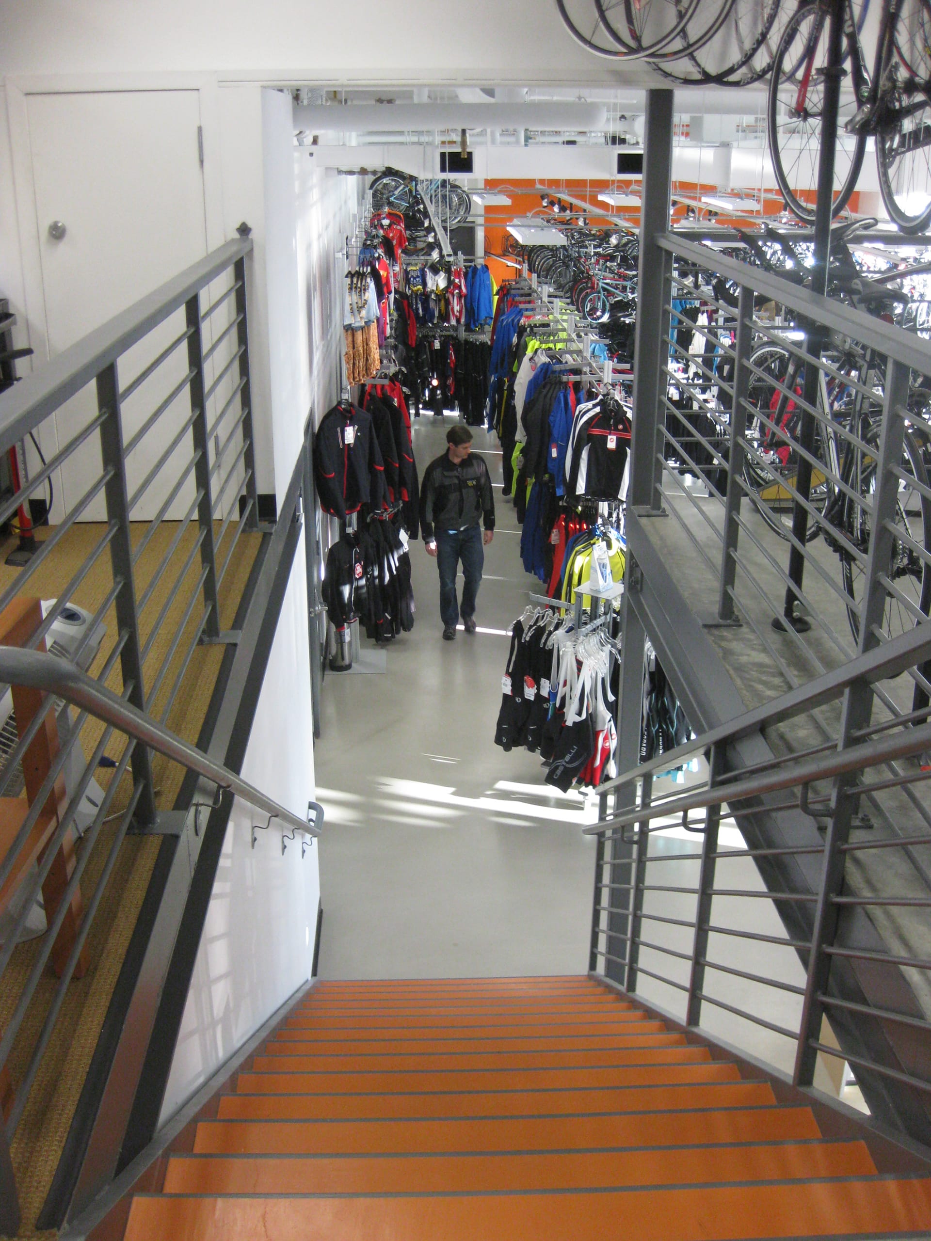 Orange staircase leading from the mezzanine to the main sales floor of a bicycle shop.