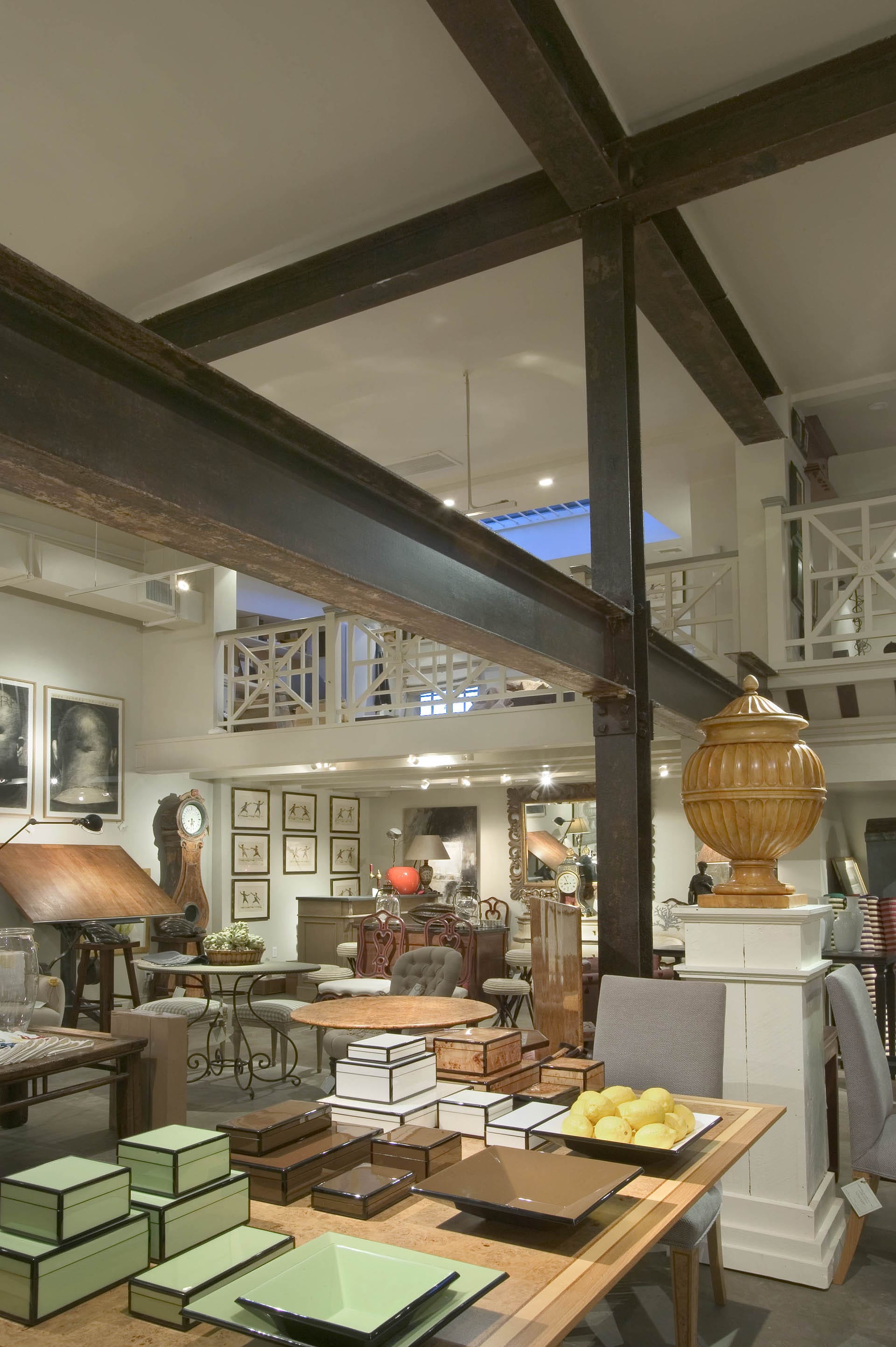 Aged metal beams used for aesthetics and support create an X on the ceiling of an antique store stocked with merchandise.