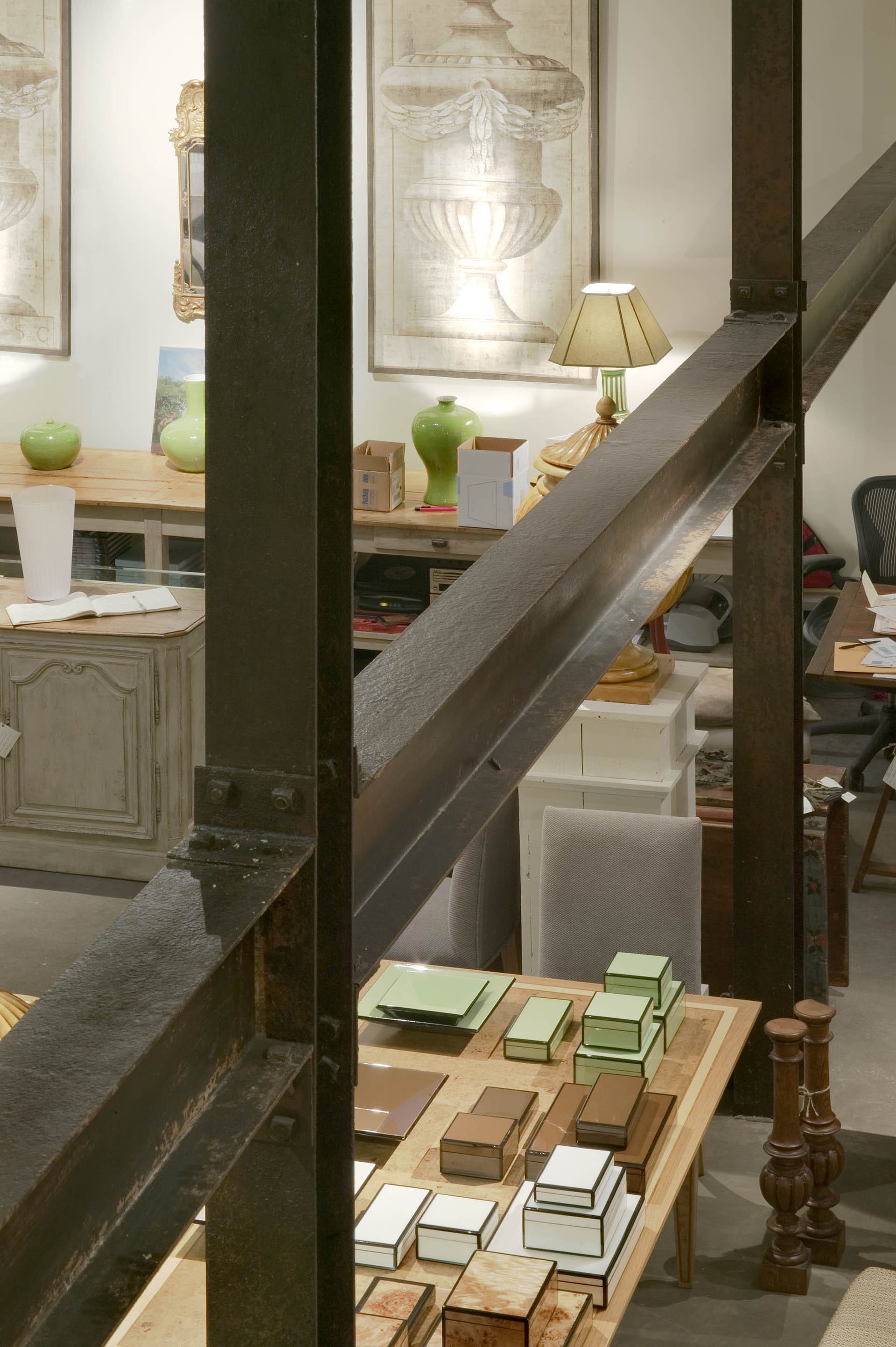 Two aged metal support columns are connected by a steal beam in a double-height space in an antique store.