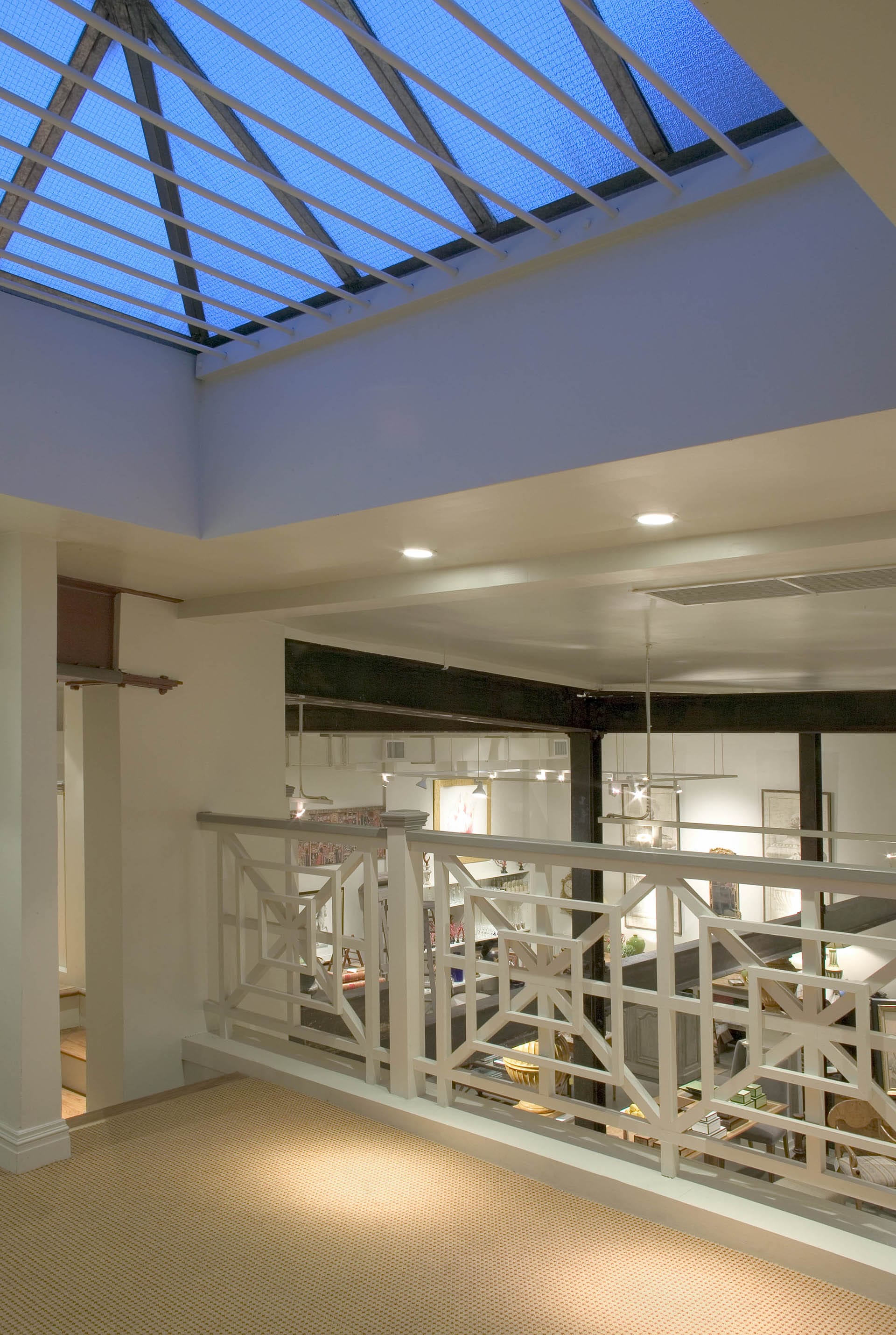 View of a large skylight from the mezzanine of an antique shop in Manhattan, NY. Beyond the decorative railing, the main sales floor peeks through.