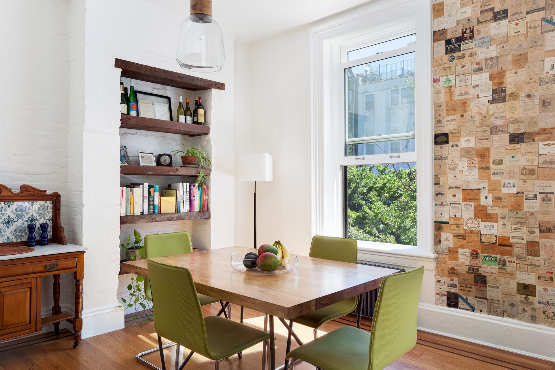 Dining area with green chairs and a wall of wine labels preserved from before the renovation.