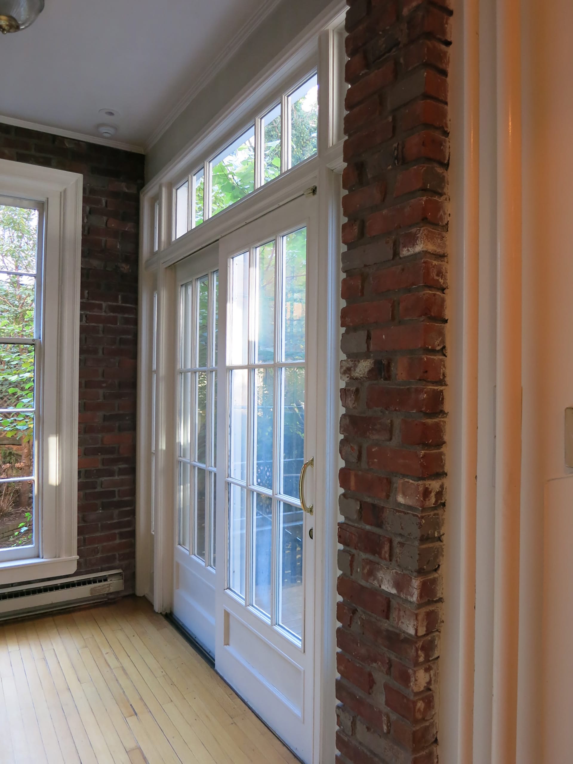 Informal dining area with exposed brick and glass doors leading out to a side patio in a Brooklyn Heights home, before our renovation.