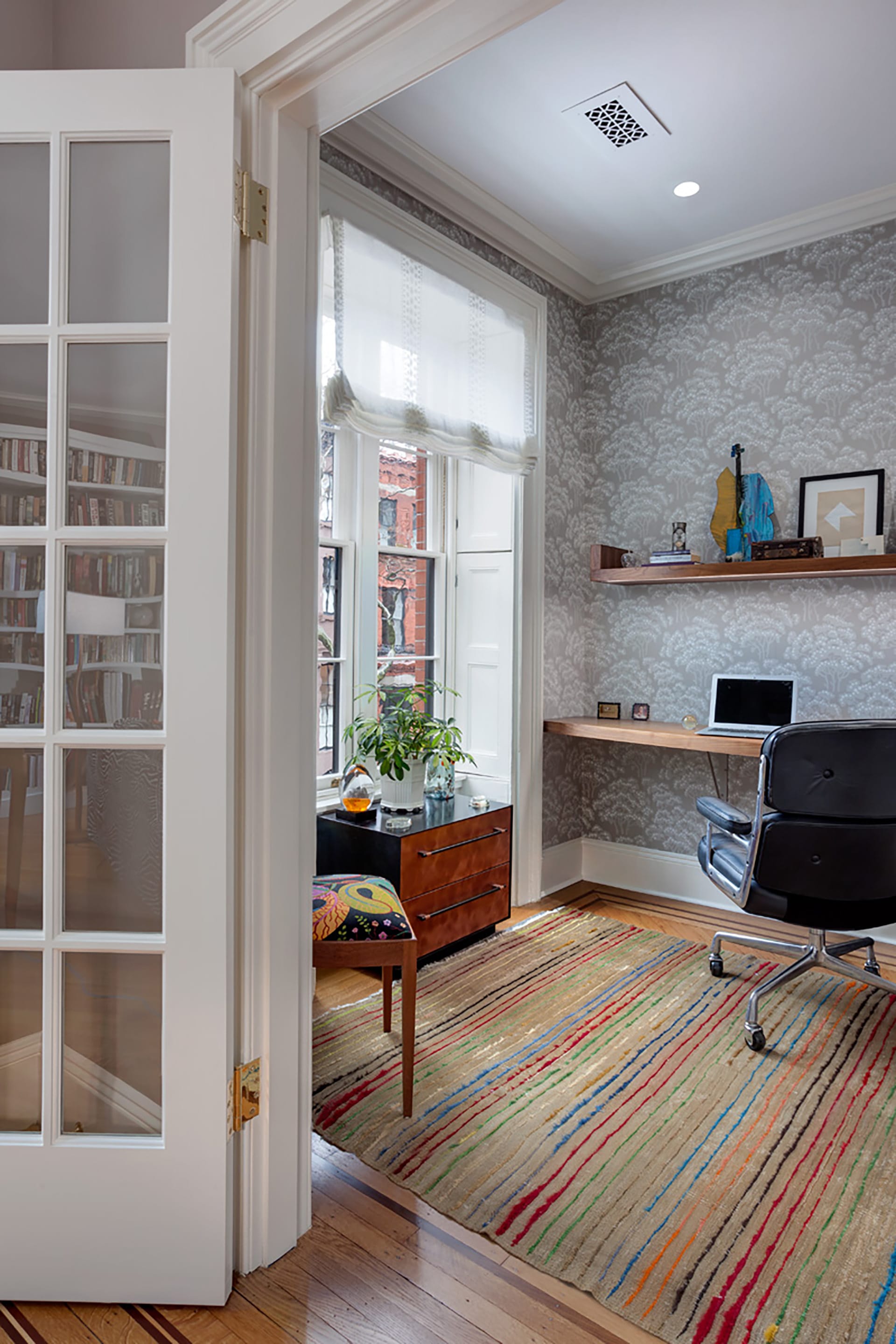 Office space in a Brooklyn Heights home with grey wallpaper, striped rug, and a set of French doors to close the space off.
