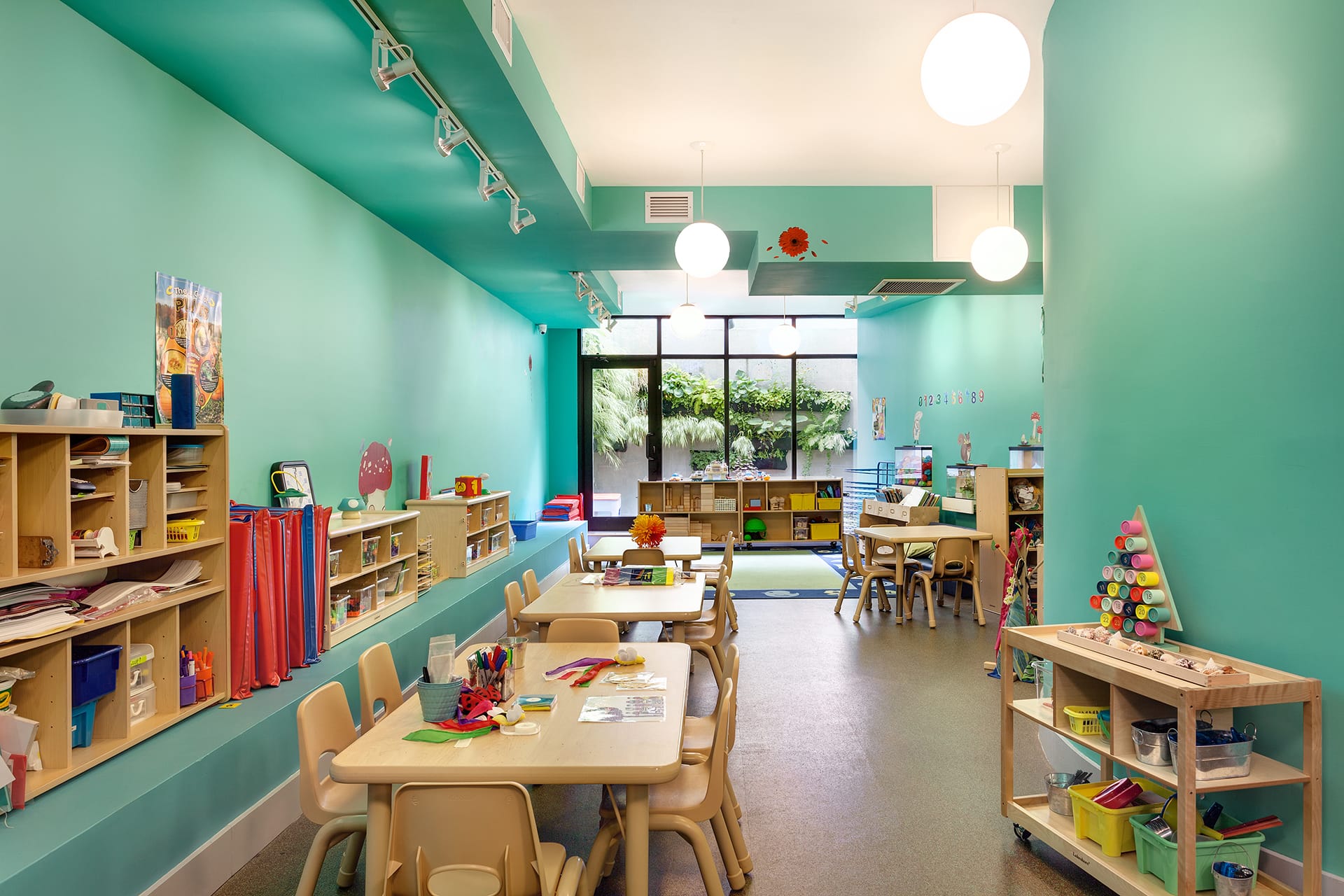 Teal-painted classroom with spherical pendant lights and a door leading to the rear yard