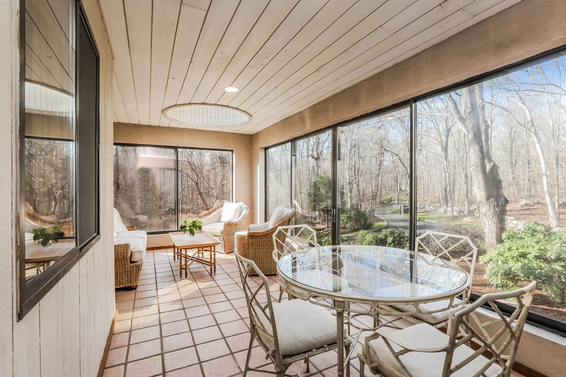 Dining area with a glass tabletop, large wraparound windows, tile floors