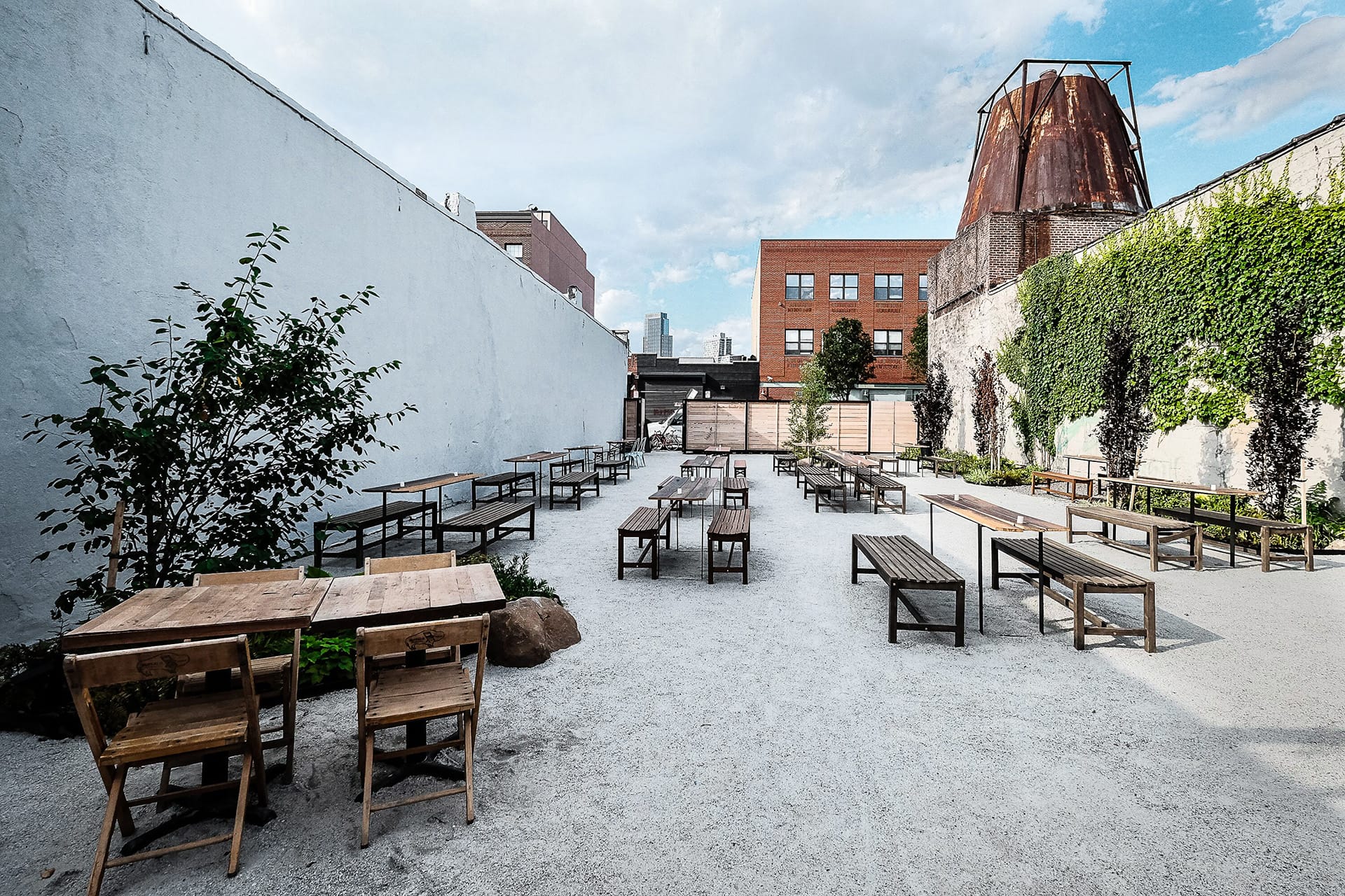 Gravel covered yard in Gowanus, Brooklyn, with many picnic tables for visitors to use.