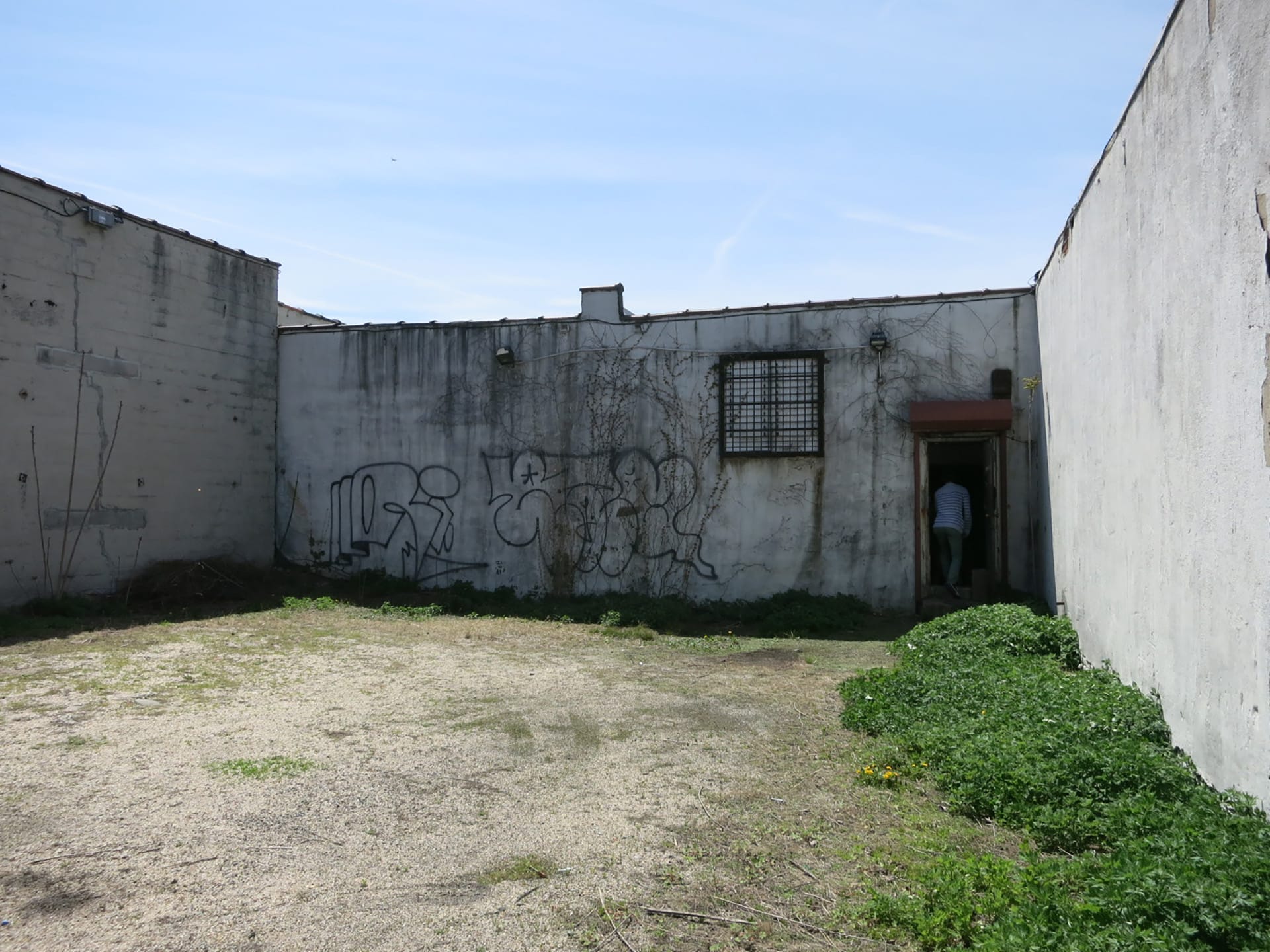 Exterior of an abandoned building before our renovation. An empty lot between two buildings creates a courtyard in front of the building.