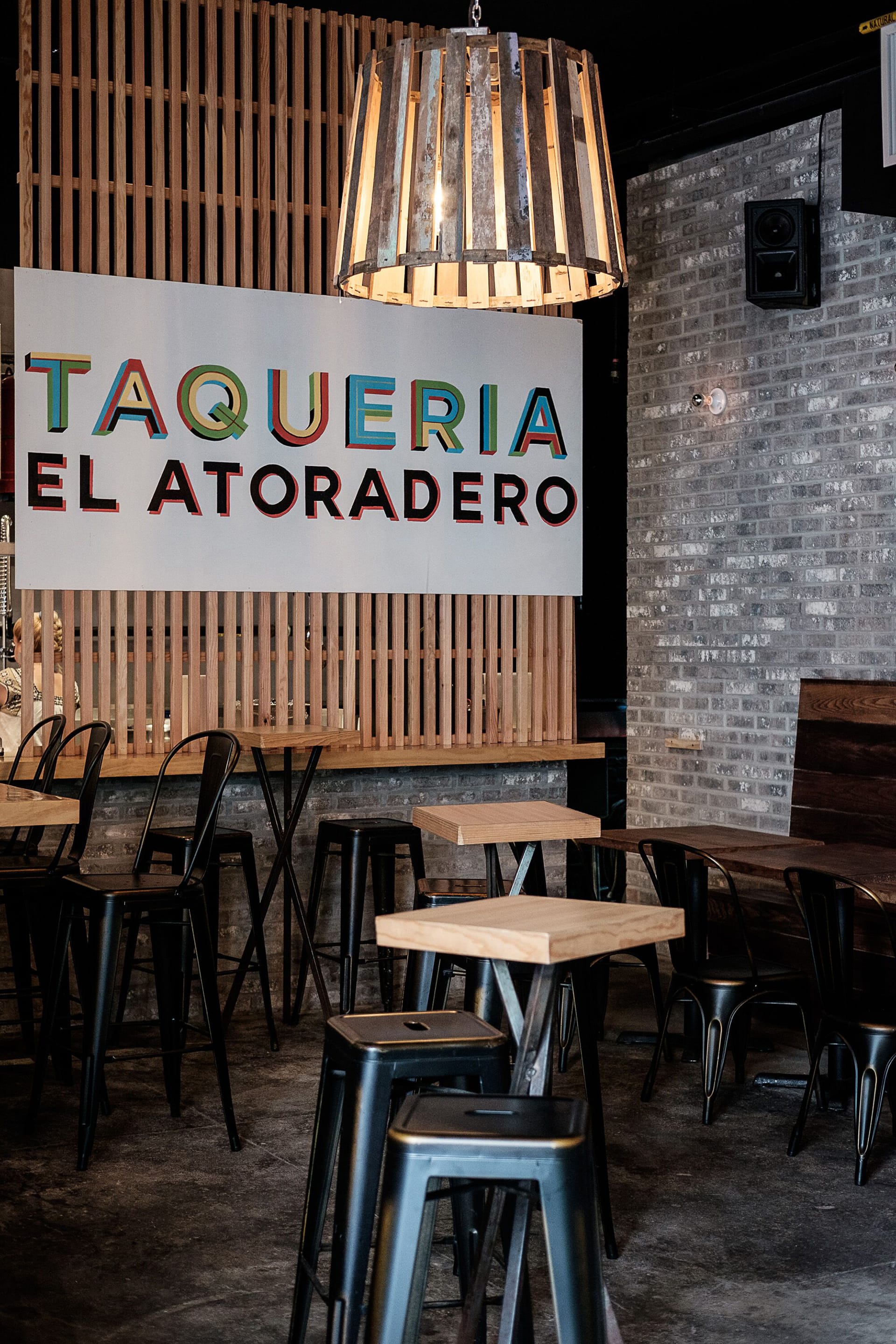 Inside of the taqueria at Parklife, with exposed brick on one wall, wood slats on the other, and a sign reading 