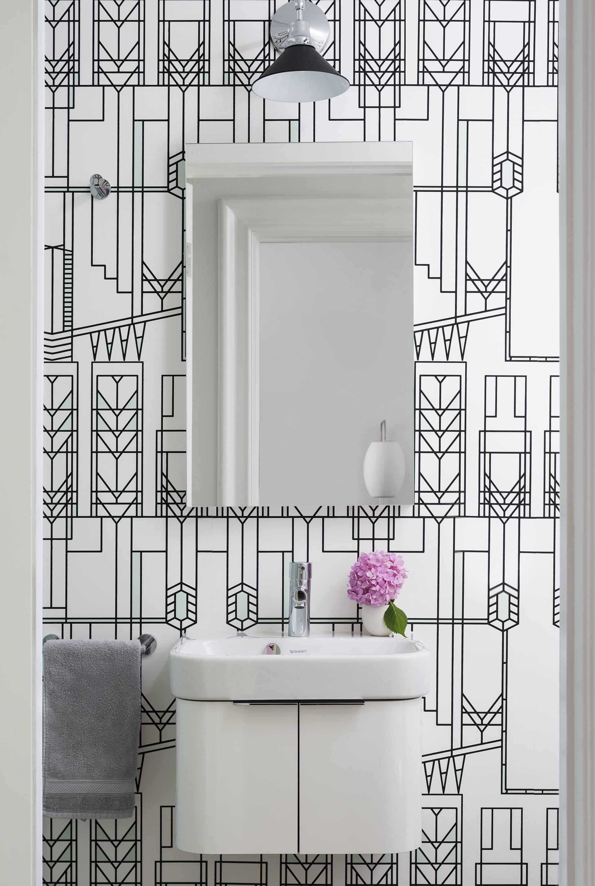 Guest bathroom with black and white wallpaper, white floating vanity, and pink flowers.